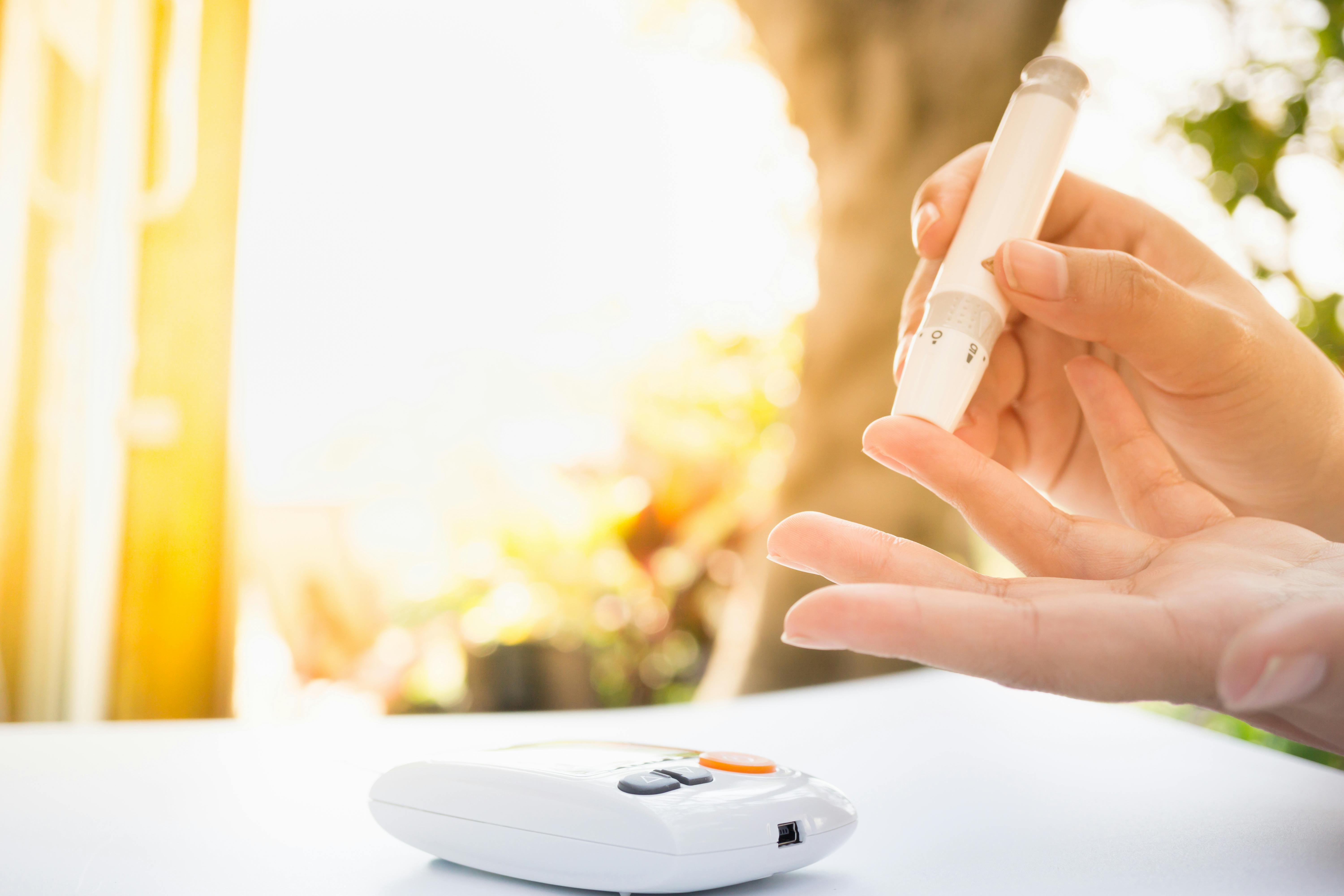 Medicine, Diabetes, Glycemia, Health care and people concept – close up of female using lancelet on finger to checking blood sugar level by Glucose meter